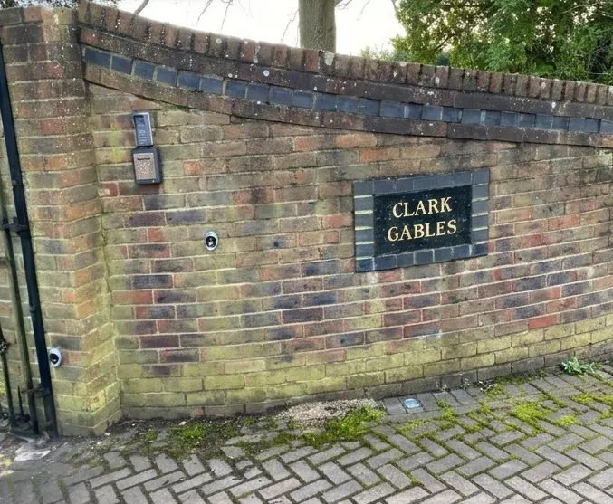 Brick boundary wall streaked with green algae before cleaning
