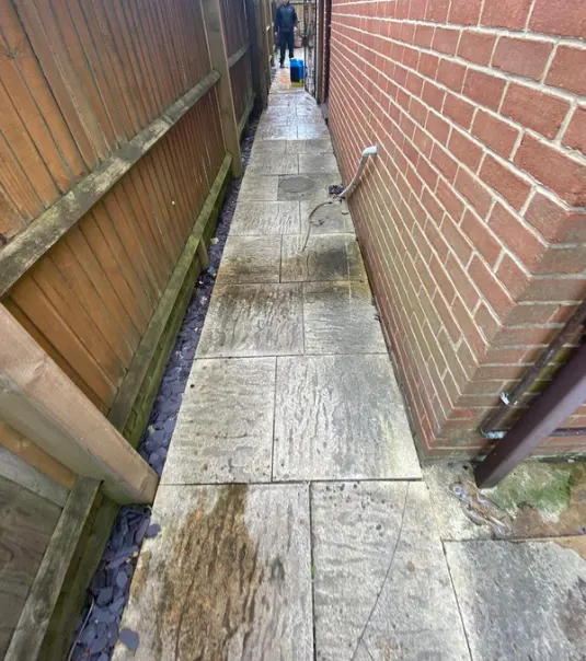 Narrow side path with dark, dirty slabs before cleaning